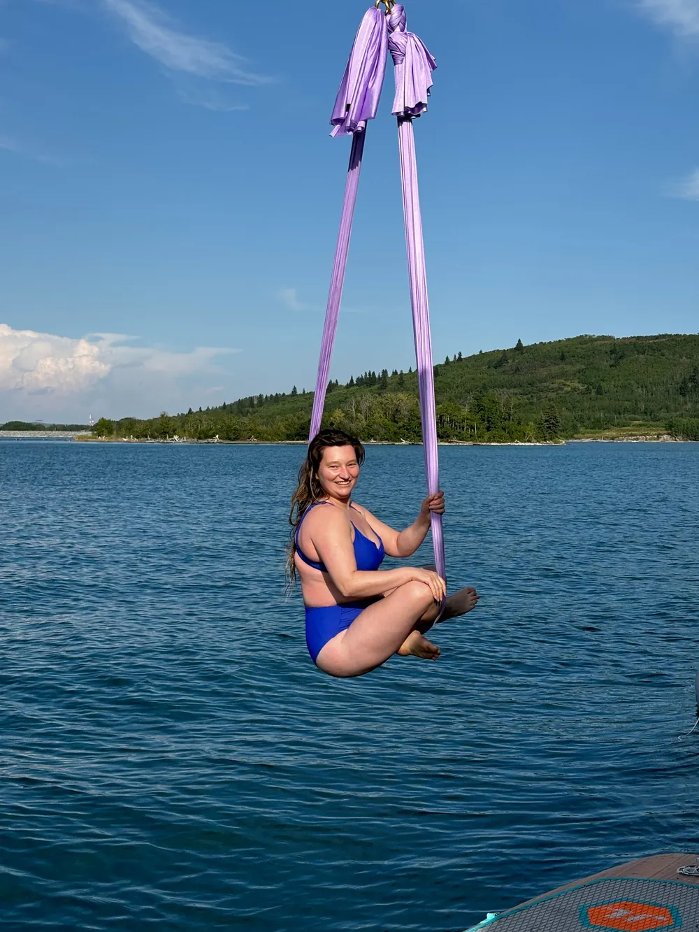 A guest seated in the silks, suspended above the water