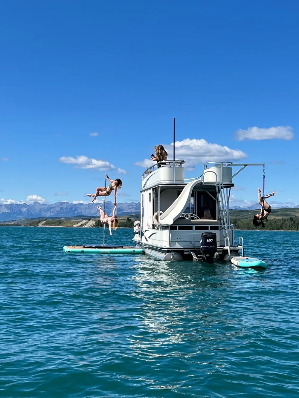 The AquaStudio moored on Ghost Lake with its water slide down and paddleboards alongside