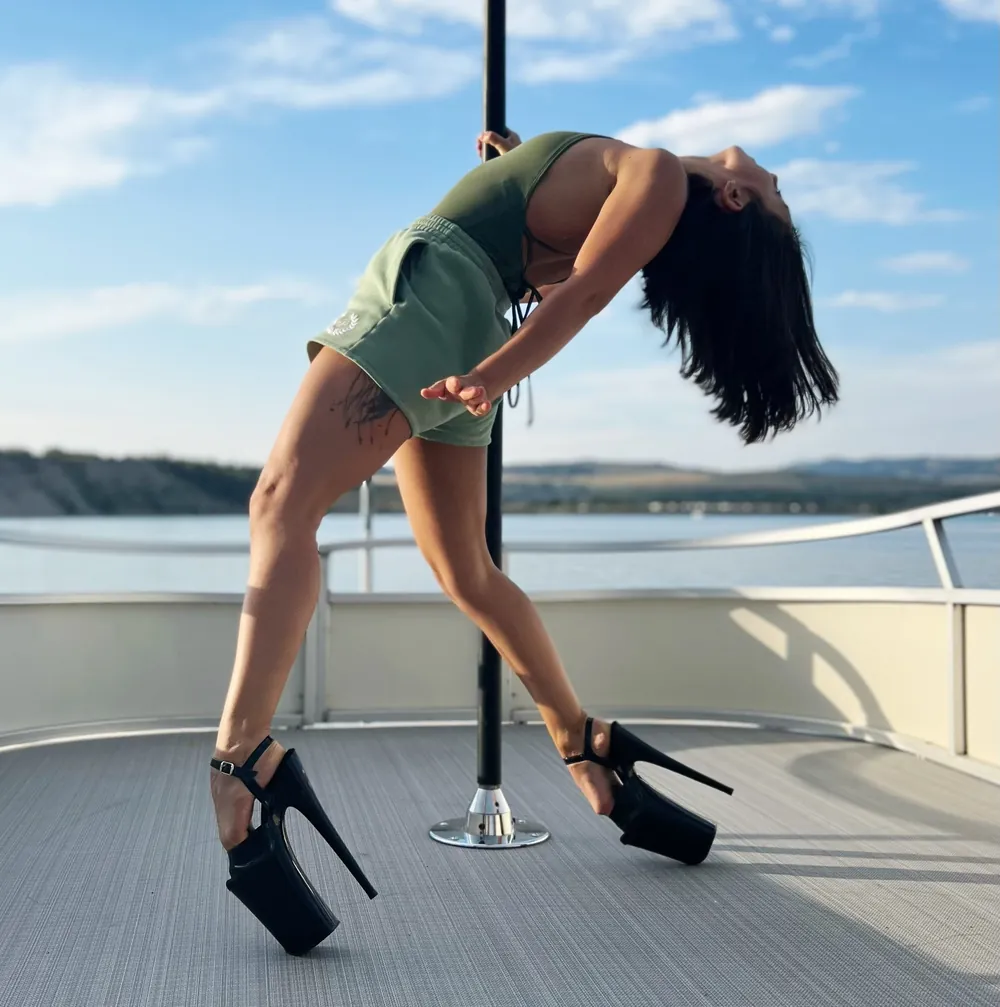 A dancer in heels bending back on the top-deck pole