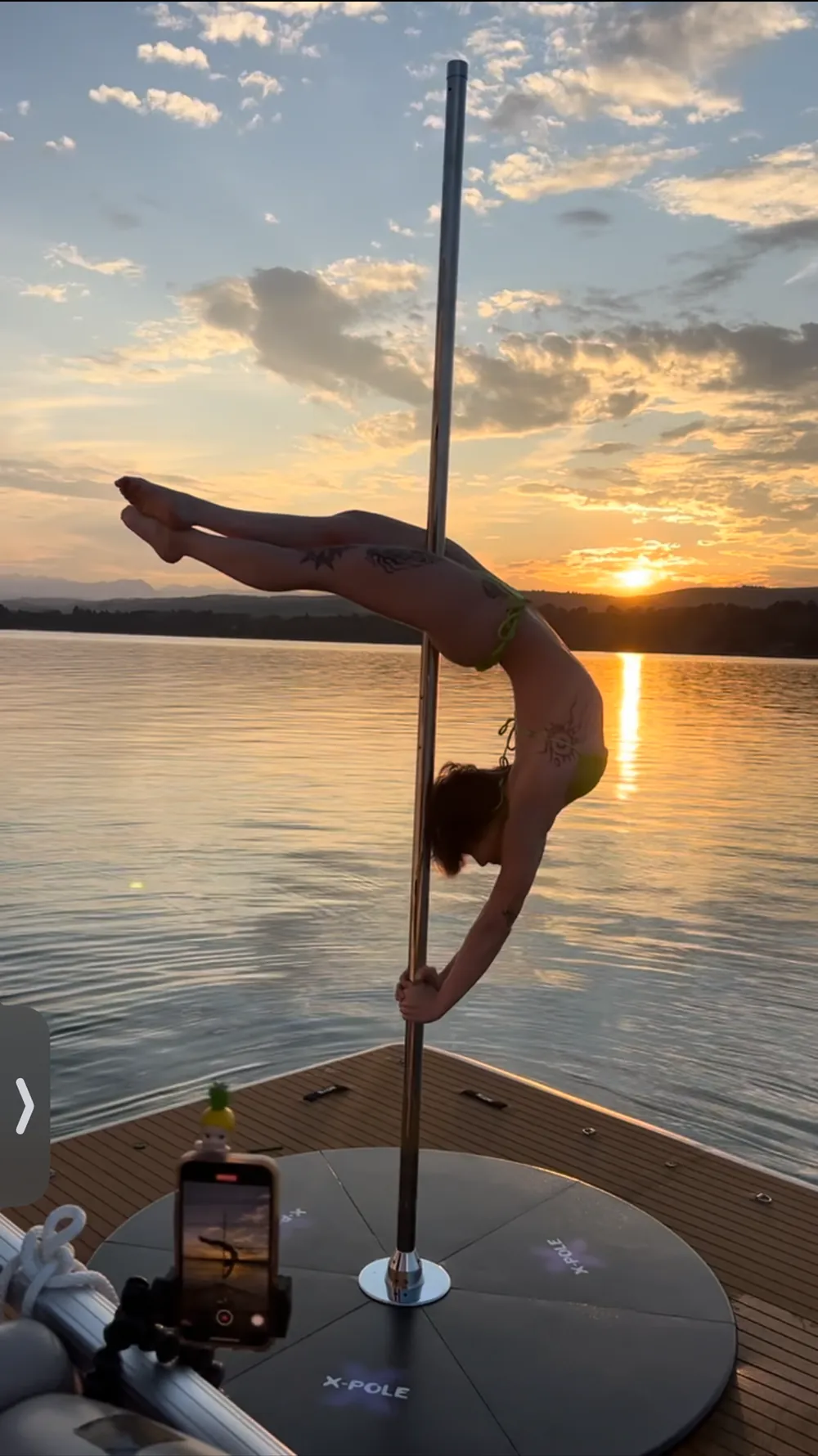 A dancer on the deck pole against a gold sunset
